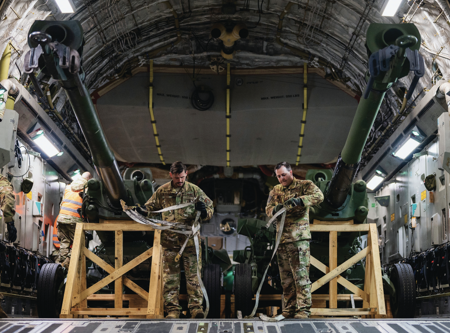 Staff Sergeant Evan Minca, 517th Airlift Squadron loadmaster, and Captain Andrew Miller-Bissell prepare to offload M777 howitzers from C-17Globemaster III in Eastern Europe, May 2, 2022 (U.S. Air Force/Shawn White)